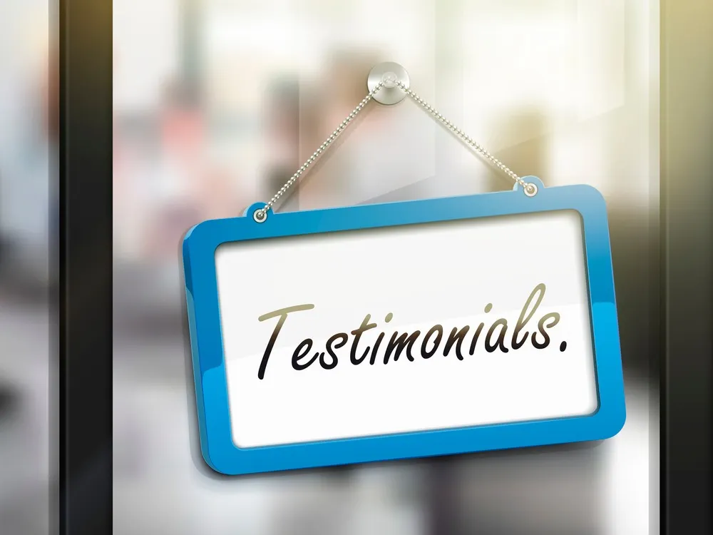 A blue sign that says testimonials hanging on a glass door.